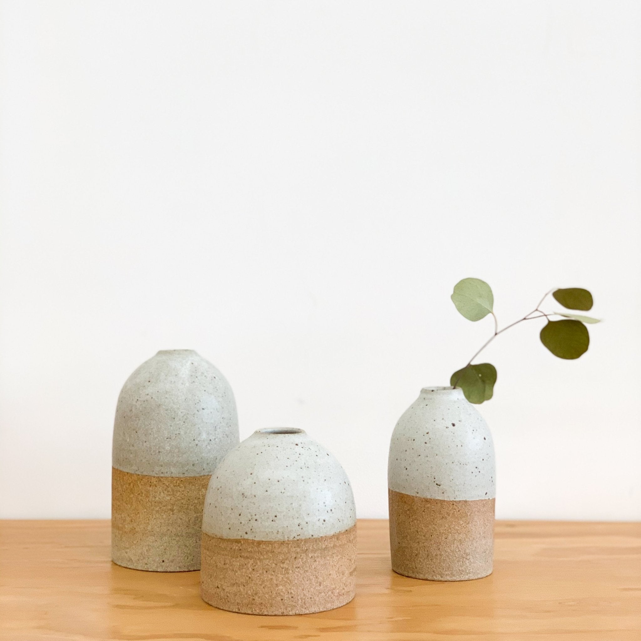 A cluster of Tomoro Morisaki&#39;s organic and rounded bud vases with dry leaf